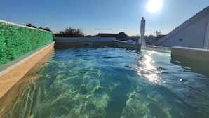 A swimming pool with clear water, surrounded by a low wall and a green hedge. - Apartment Penthouse Ivan (Drnis)