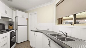 A modern kitchen with white cabinetry, a black countertop, a double sink, and a window with a view.