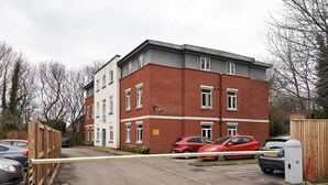 A multi-story residential building with a gated parking area.