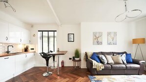 A modern living space with a kitchen, dining area, and a cozy seating area with a sofa and a floor lamp.