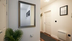 A hallway with a framed picture, a door, a radiator, and a sign with house rules.