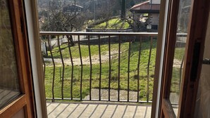 A room with a balcony, a bed, and a view of a hilly landscape. - Apartment in the midst of nature that will help regenerate your body and mind (Castiglione dei Pepoli)