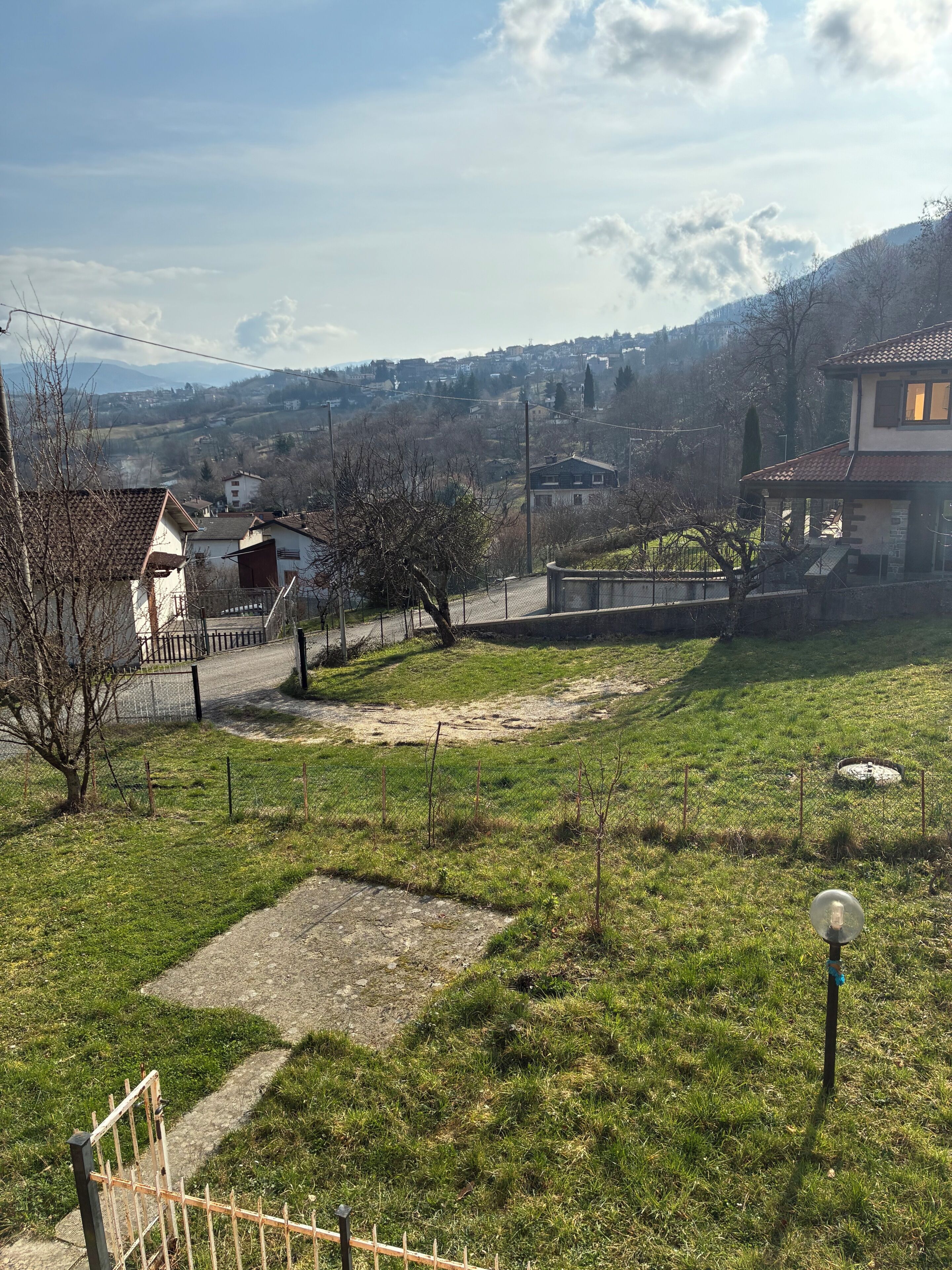 A residential area with houses, a paved path, and a grassy field.