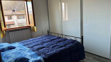 Une chambre à coucher avec un lit, un radiateur, une fenêtre et une armoire.