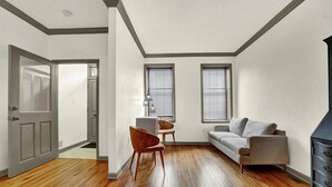 A room with hardwood flooring, a gray sofa, a wooden chair, and a dresser. - NEW Downtown York 2B Getaway. Modern Comfort. (York)