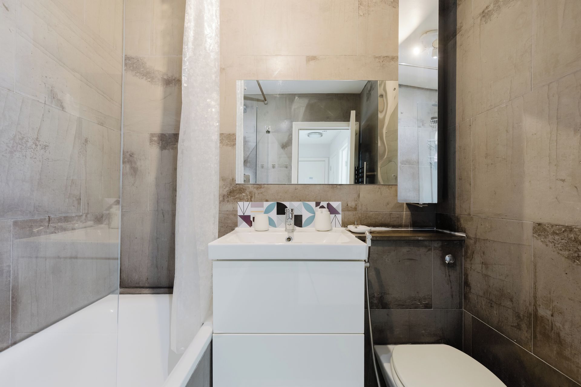A bathroom with a white sink, a mirror, and a toilet.