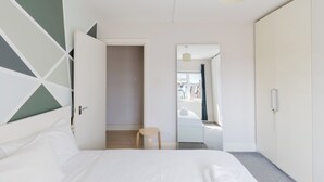 Une chambre à coucher avec un lit, une chaise, une armoire et un miroir.