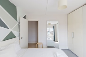 A bedroom with a bed, a chair, a wardrobe, and a mirror. - Sunny 1BD Flat in the Heart of Maida Vale (Greater London)