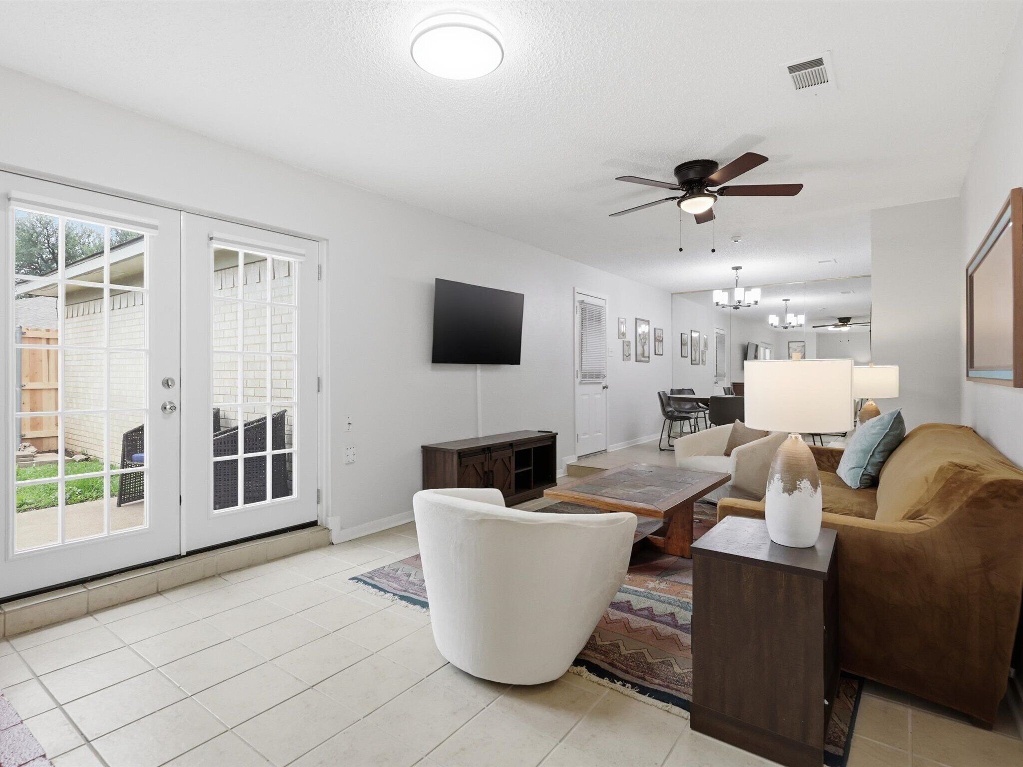 A living room with a ceiling fan, a flat-screen TV, a sofa, a coffee table, and a dining area with chairs.