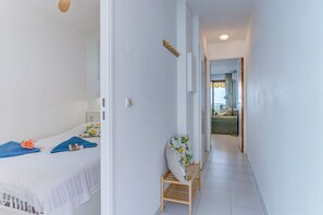 A hotel room with a bed, a bench, a small table, and a door leading to another room. - ANGE GARDIEN VI AP4502 By Riviera Holiday Homes (Villefranche-sur-Mer)