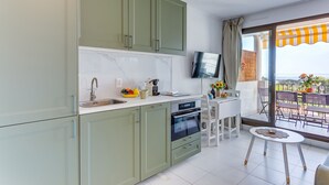 Een moderne keuken met een ingebouwde oven en een eethoek met een kleine tafel en stoelen.