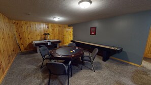 Ein Raum mit Billardtisch, Stühlen, Kicker und Dartscheibe.