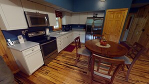Una cucina compatta con microonde, fornelli, frigorifero e tavolo da pranzo in legno con sedie.