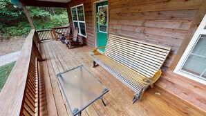 Un pontile in legno con un tavolo in vetro e panche, una porta verde e una finestra.