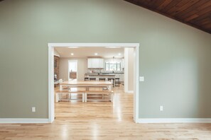 An open-plan living area with a kitchen in the background, wooden flooring, and a high ceiling. - Luxurious Retreat with Pool and Game Room (Logan)