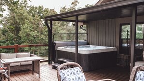 Eine Holzterrasse mit Whirlpool, Korbmöbeln und einer überdachten Sitzgruppe.