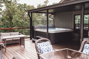 Eine Holzterrasse mit Whirlpool, Korbmöbeln und einer überdachten Sitzgruppe.