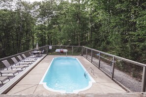 Una piscina rectangular con una escalera de metal, rodeada por una barandilla metálica y protegida por un toldo.