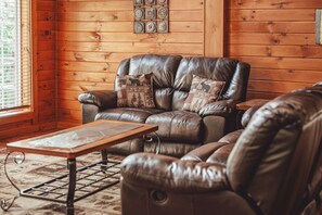 A leather sofa with patterned cushions in a room with wooden walls and a window. - Scotts Creek Cabins - Hem Loch (Logan)