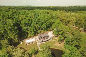 A large house surrounded by dense forest, with a swimming pool and a dock extending into a lake. - Scotts Creek Cabins - Hem Loch (Logan)