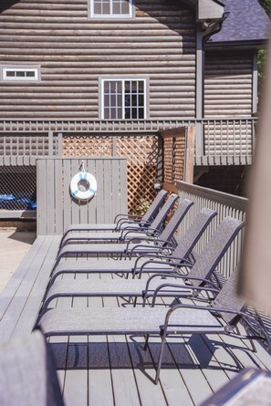Terraza de madera con sillas de metal y un flotador en la cerca.