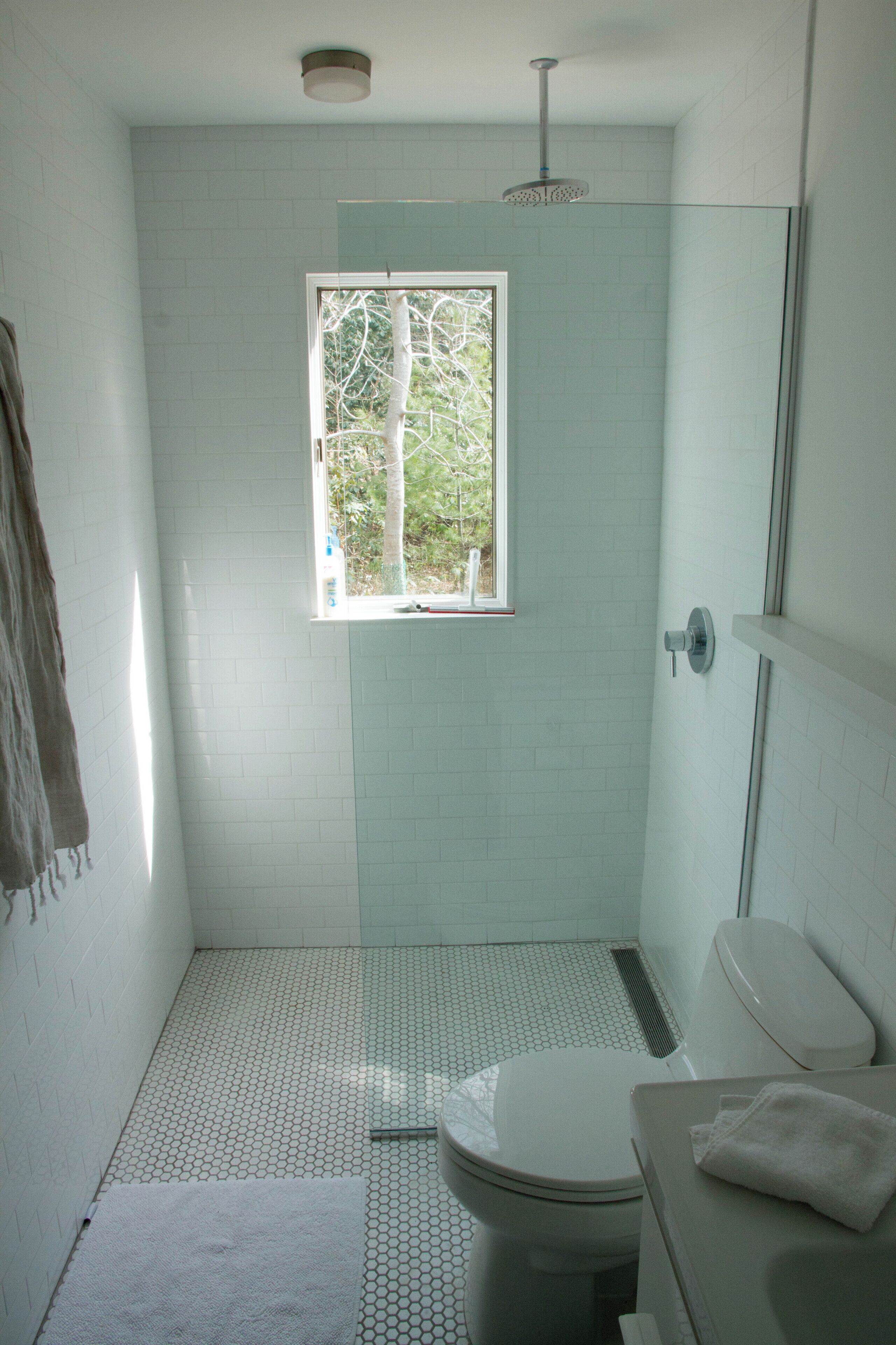 Une salle de bain avec des toilettes, un lavabo et une douche. Il y a une fenêtre au-dessus des toilettes.