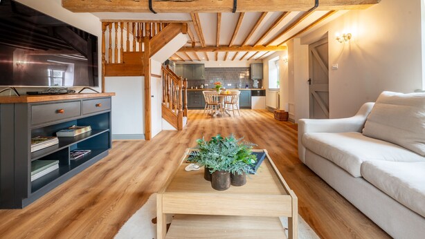 A modern living room with a wooden coffee table, a sofa, and a TV on a stand. - The Cottage at Tuffon Hall, Sible Hedingham, Suffolk (Sible Hedingham)