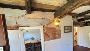 A room with exposed brick walls, a wooden ceiling, and a dining area with a table and chairs. - David & Marion's Vacation Rental: 7 minutes from Karls Erlebnisdorf/Bremerhaven and the Weser beach. (Loxstedt)