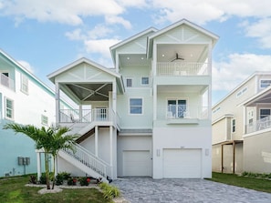 A multi-story residential building with a central staircase, balconies, and a garage. - Beach To Bay Vacation Home (Fort Myers Beach)