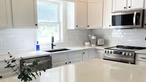 A modern kitchen with white cabinets, a central island, a microwave, and a stove. - Good Vibes LKA Lakeview with Boat Slip (Orange)