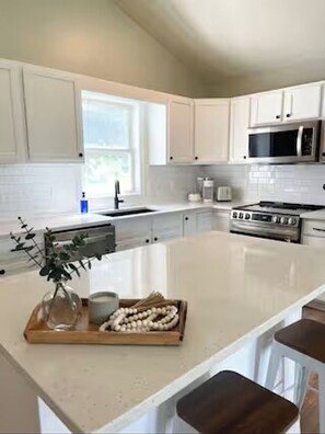 A modern kitchen with white cabinets, a central island, a microwave, and a stove. - Good Vibes LKA Lakeview with Boat Slip (Orange)
