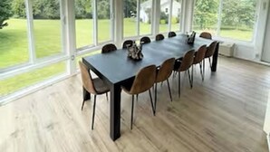 A covered dining area with a long table and chairs, large windows, and a ceiling fan. - Good Vibes LKA Lakeview with Boat Slip (Orange)