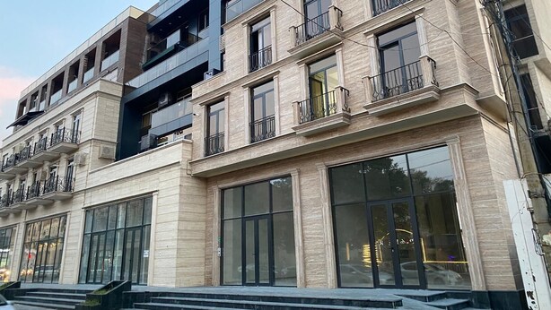 A multi-story building with large windows, balconies, and a modern architectural design.