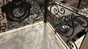 A balcony with ornate metal railings overlooking a cityscape.