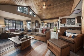 A spacious living area with a high ceiling, wooden furniture, and large windows providing natural light. - Whispering Pines | EV Chrg, Near Trails, Dogs Ok! (Big Bear)