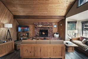 A cozy living room with a fireplace, a Netflix TV, and wooden furniture. - Whispering Pines | EV Chrg, Near Trails, Dogs Ok! (Big Bear)