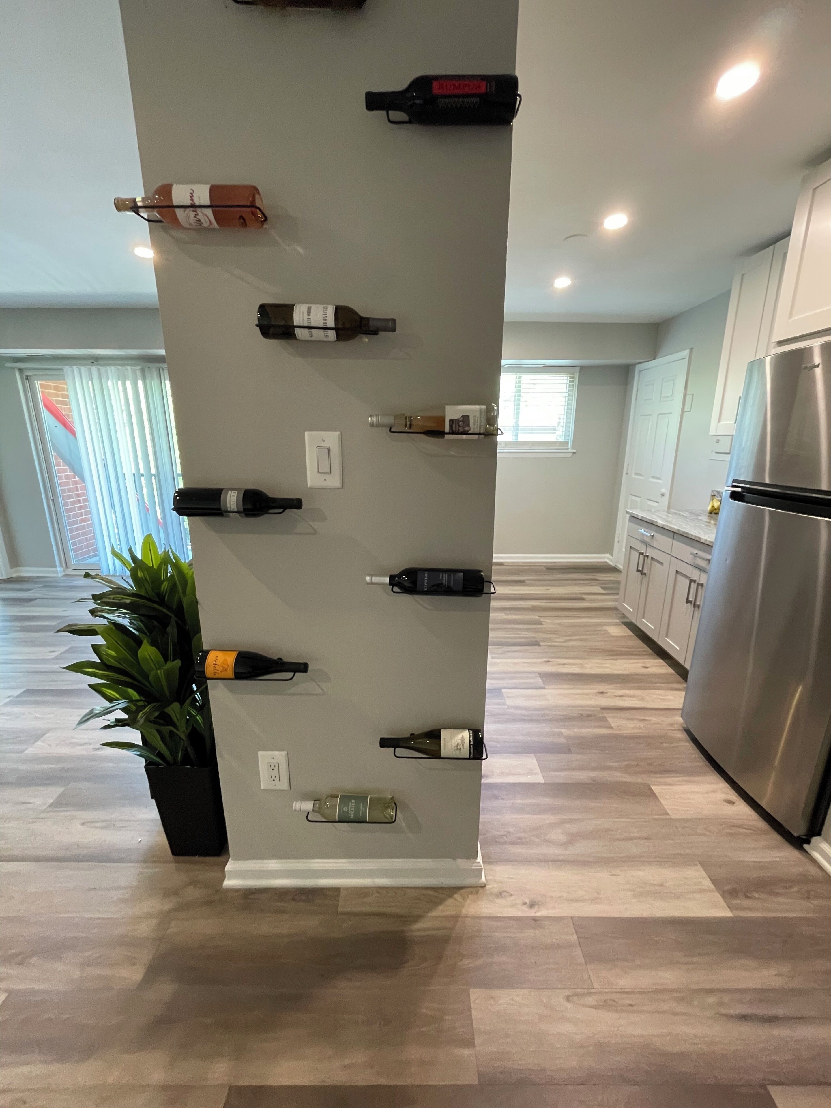 Eine Küche mit einer Weinschlange voller Flaschen, einem Kühlschrank und einem Blumentopf.