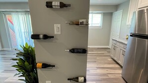 Una cocina con una vinoteca que alberga varias botellas, un refrigerador y una planta en maceta.