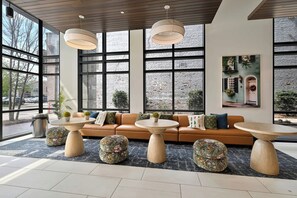 A modern interior with a sofa, round tables, and large windows. - Spacious & Modern Stay near King St - Sleeps 6! (Charleston)