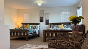 Une chambre avec deux lits, un canapé, un tapis et un lustre.