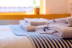 Ein ordentlich bezogenes Bett mit gefalteten Handtüchern und einer gestreiften Decke.