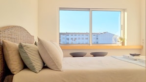 A bedroom with a bed, pillows, a window, and a view of buildings. - ihTop | 4 Bedrooms | 3 Bathrooms | 3 Balconies (Espinho)