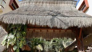 Una estructura con techo de paja y estructura de madera, rodeada de plantas tropicales.