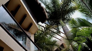 Un edificio moderno con fachada de vidrio, una palmera y una estructura de techo de paja.