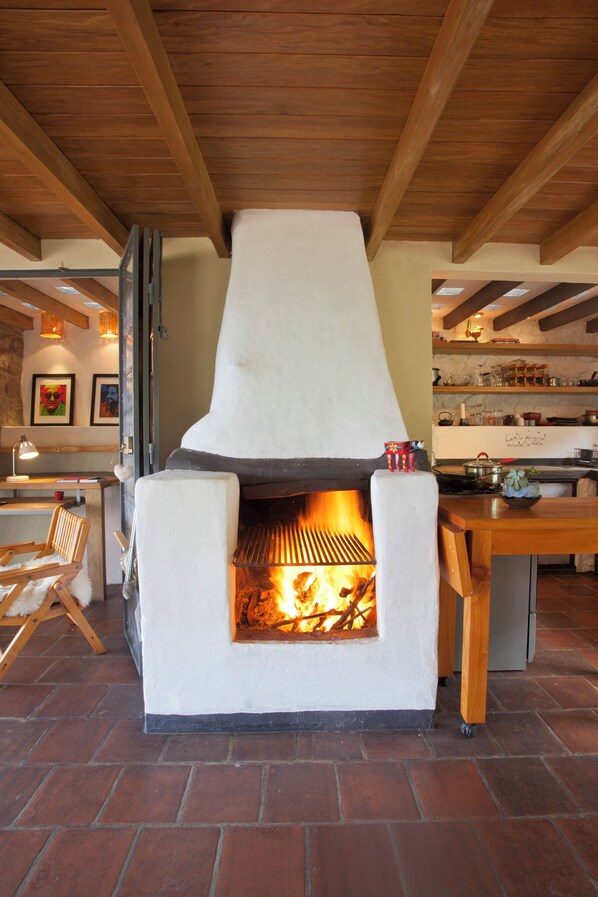 A wood-burning pizza oven with a brick floor and wooden beams on the ceiling.