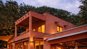 A modern two-story house with a patio area, outdoor seating, and potted plants.