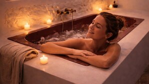 A spa room with a bathtub, candles, and a painting of cacti.