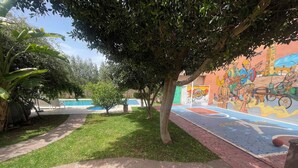 Un patio con piscina, un mural y una cancha de baloncesto.