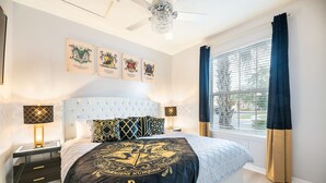 A bedroom with a large bed, a chandelier, a window with curtains, and wall-mounted artwork. - NEW!Racing Simulator|Game Room|Movie Room|Sleep 21 (Kissimmee)