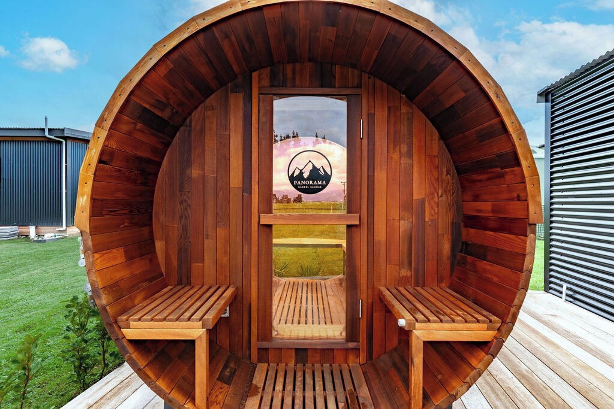 A wooden sauna with a logo, two benches, and a view of a landscape.